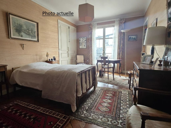 Chambre d'un appartement à Paris 17ème avec lit, meubles en bois et tapis au sol.