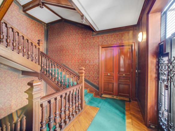 Escalier en bois et moquette verte dans un immeuble ancien à Paris 17ème.