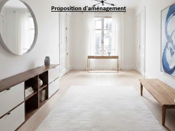 Intérieur d'un appartement lumineux avec un miroir rond, un meuble en bois et un tableau sur le mur.