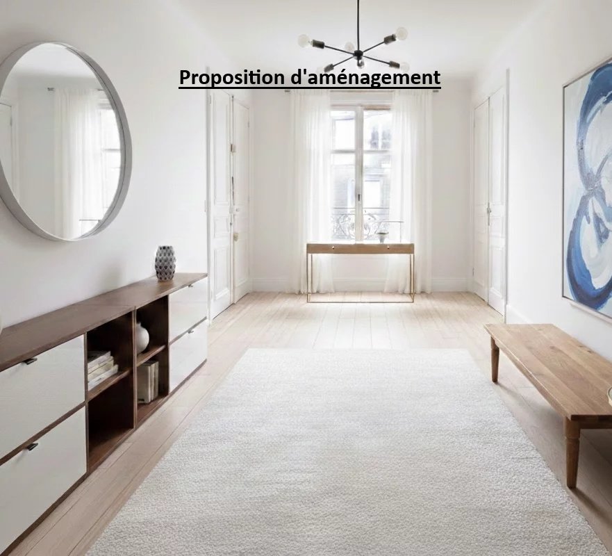 Intérieur d’un appartement familial à Paris 17ème Intérieur d'un appartement lumineux avec un miroir rond, un meuble en bois et un tableau sur le mur.