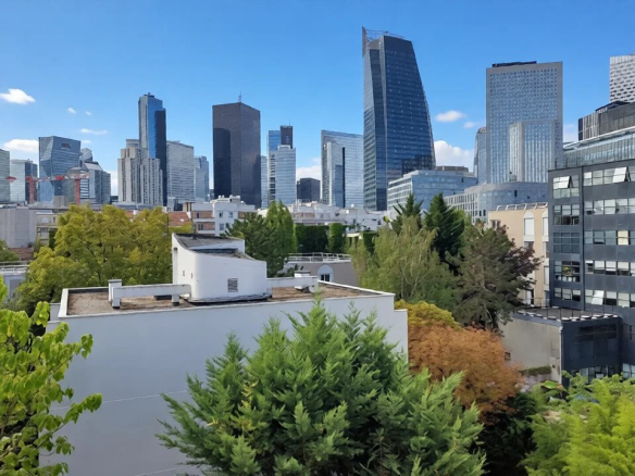 Vue depuis un appartement à Courbevoie avec des immeubles modernes et des arbres au premier plan.