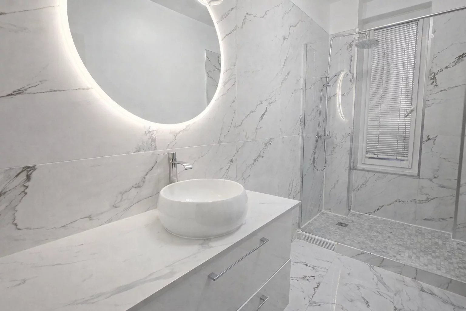 Modern bathroom with shower and marble sink, circular lighting.