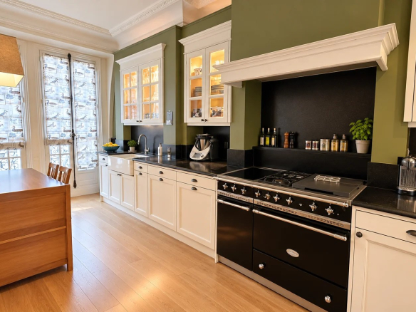 Cuisine moderne d'un duplex à Paris 17ème, avec meubles blancs et mur vert.