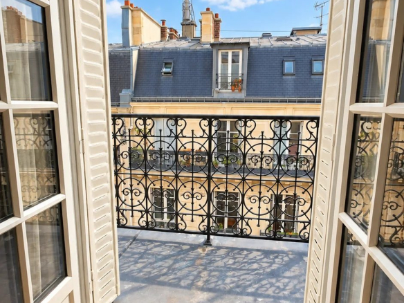 Vue depuis un balcon d'un duplex à Paris 17ème, ciel bleu et balustrade en fer forgé.