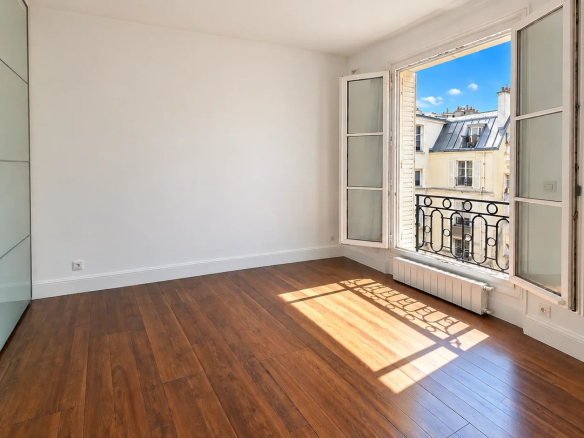 Bright room with windows in Paris 16th arrondissement, parquet flooring and white walls.
