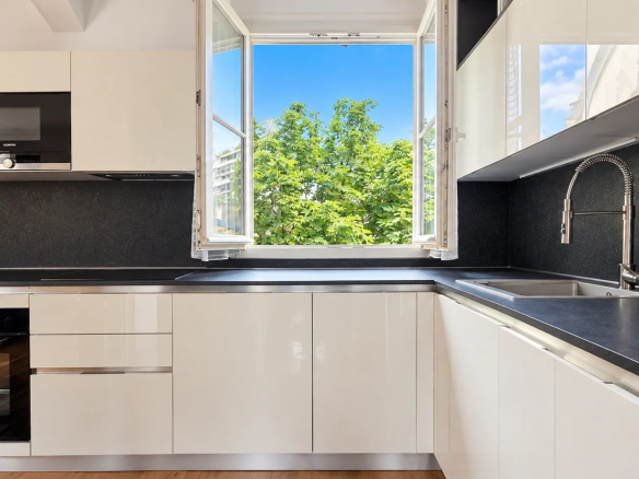Modern kitchen with windows opening onto a green space, apartment in Paris 16th arrondissement.