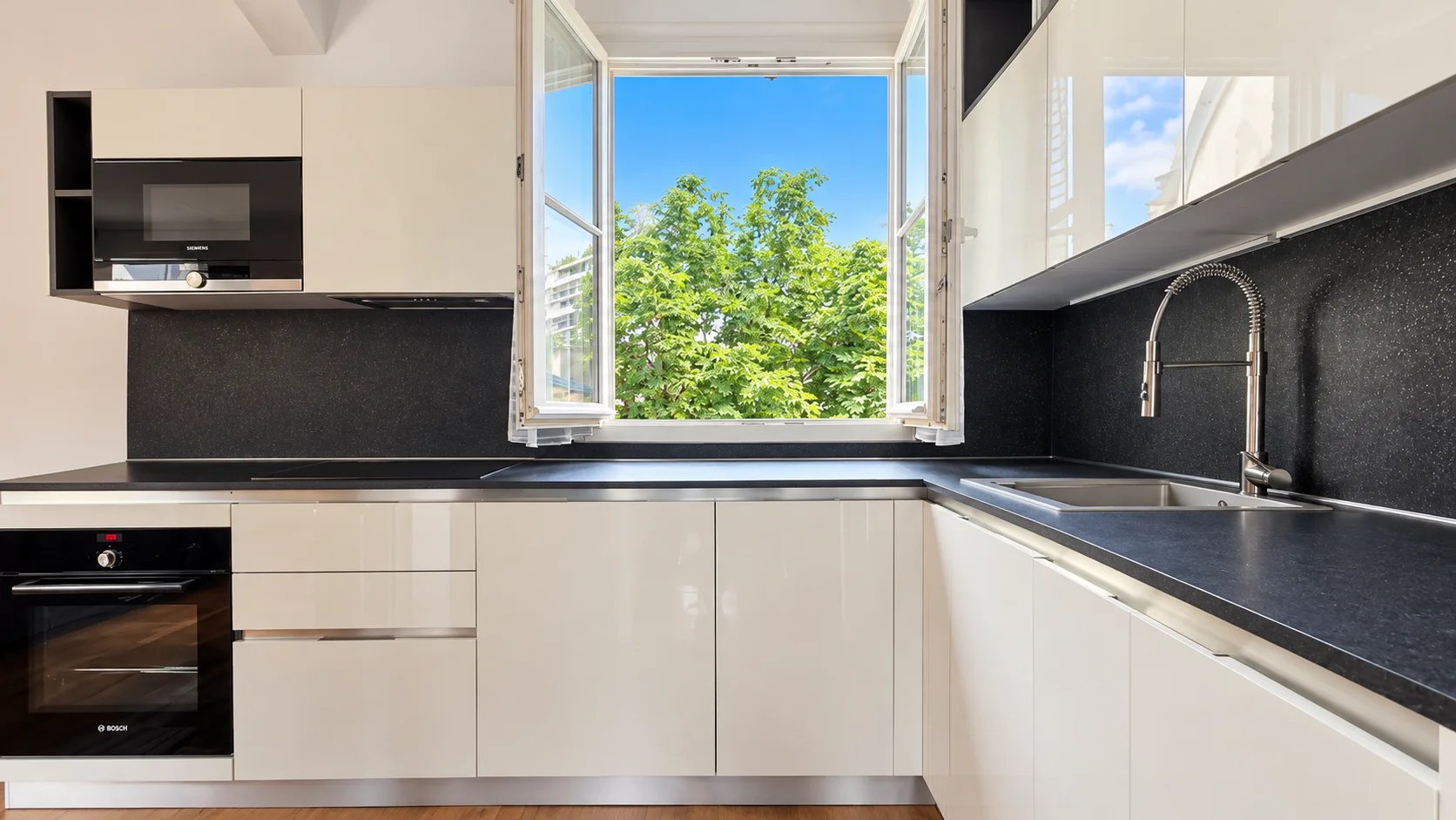 Kitchen of an apartment in the 16th arrondissement of Paris Modern kitchen with windows opening onto a green space, apartment in Paris 16th arrondissement.