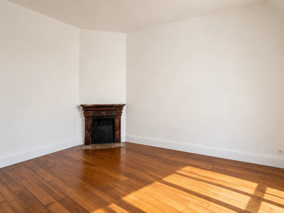 Interior of an empty apartment with parquet flooring and fireplace, abundant natural light.