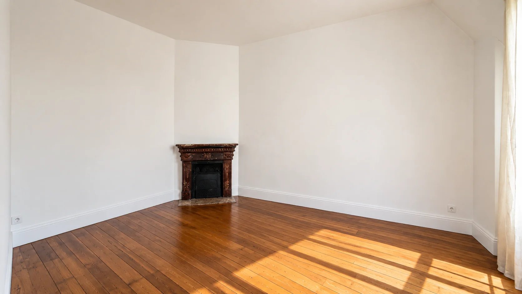 Interior of an apartment in the 16th arrondissement of Paris Interior of an empty apartment with parquet flooring and fireplace, abundant natural light.
