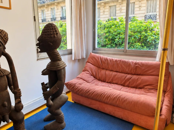 Living room of a family apartment with pink sofa and wooden sculptures, Paris 16th arrondissement.