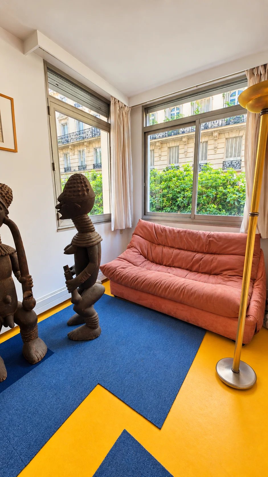 Apartment living room in the 16th arrondissement of Paris Living room of a family apartment with pink sofa and wooden sculptures, Paris 16th arrondissement.