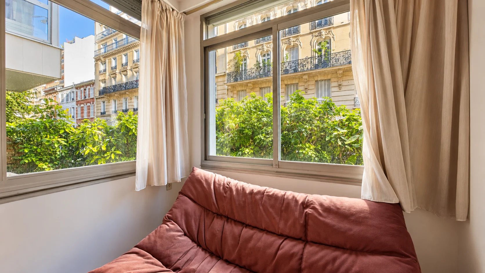 Interior of an apartment in the 16th arrondissement of Paris Interior view of an apartment with a sofa and windows overlooking a garden.