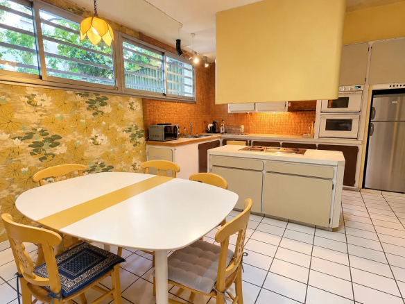 Spacious kitchen in an apartment in the 16th arrondissement of Paris with table and chairs, decorated walls.