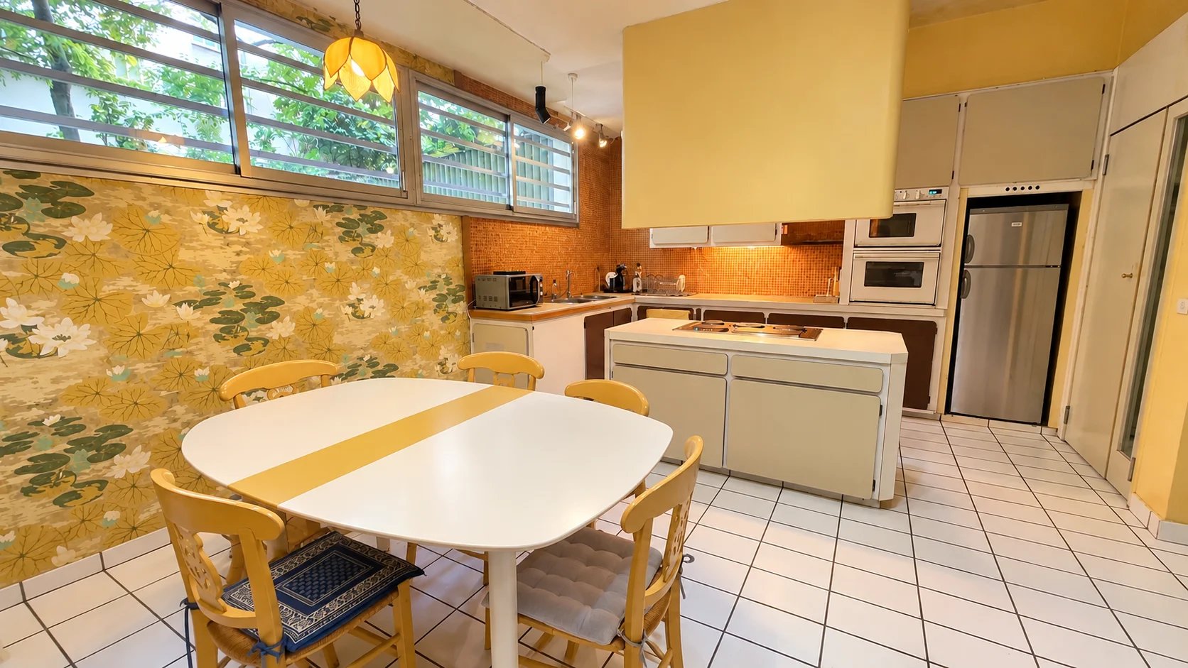Kitchen of a family apartment in the 16th arrondissement of Paris Spacious kitchen in an apartment in the 16th arrondissement of Paris with table and chairs, decorated walls.