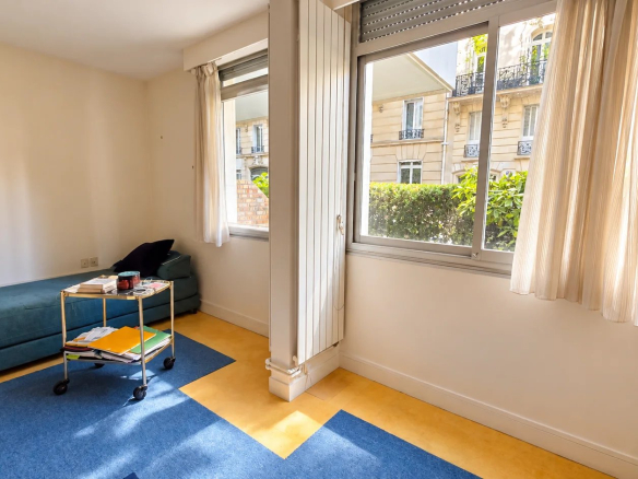 Interior of an apartment in the 16th arrondissement of Paris with a living area and windows overlooking the outside.