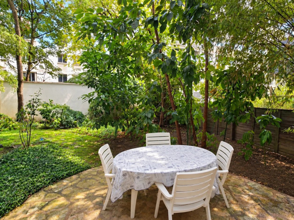 Private garden of an apartment in Auteuil, Paris 16th, with table and chairs.