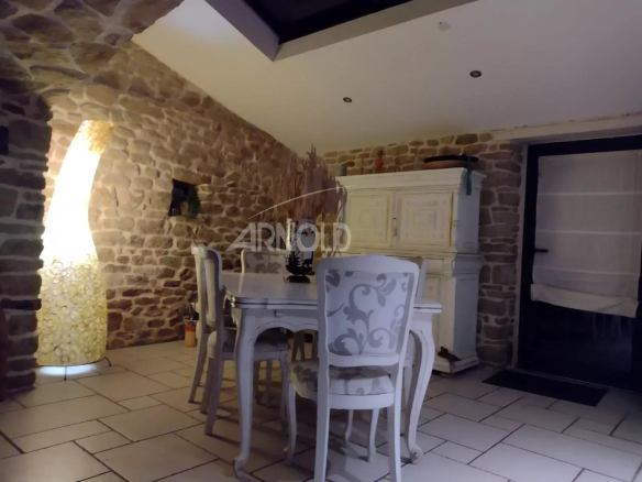 Rustic dining room with stone walls, a white carved dining table and chairs, and a tall floor lamp.
