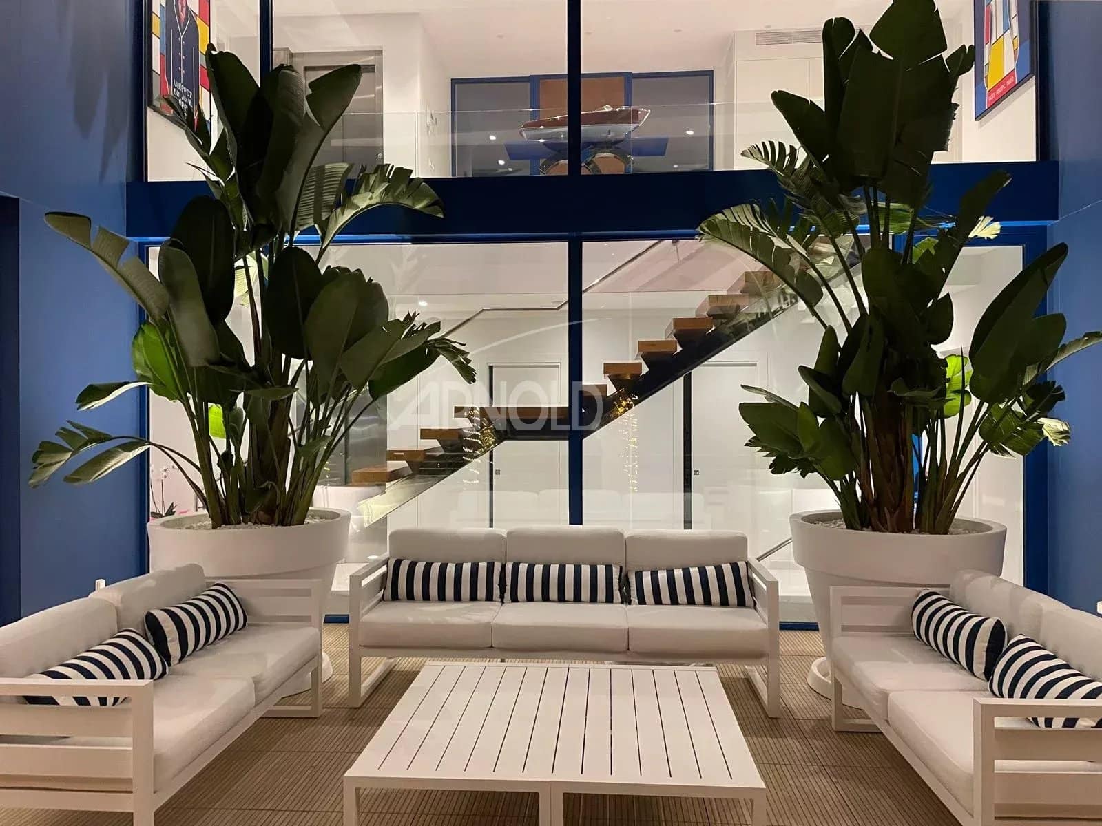 Modern interior of a villa with plants and white furniture, view of a contemporary staircase.