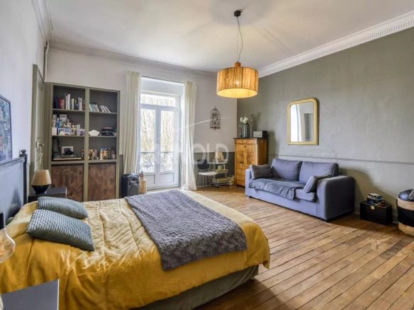 Spacious room with bed, sofa and library in a private mansion in Ancenis-Saint-Géréon.