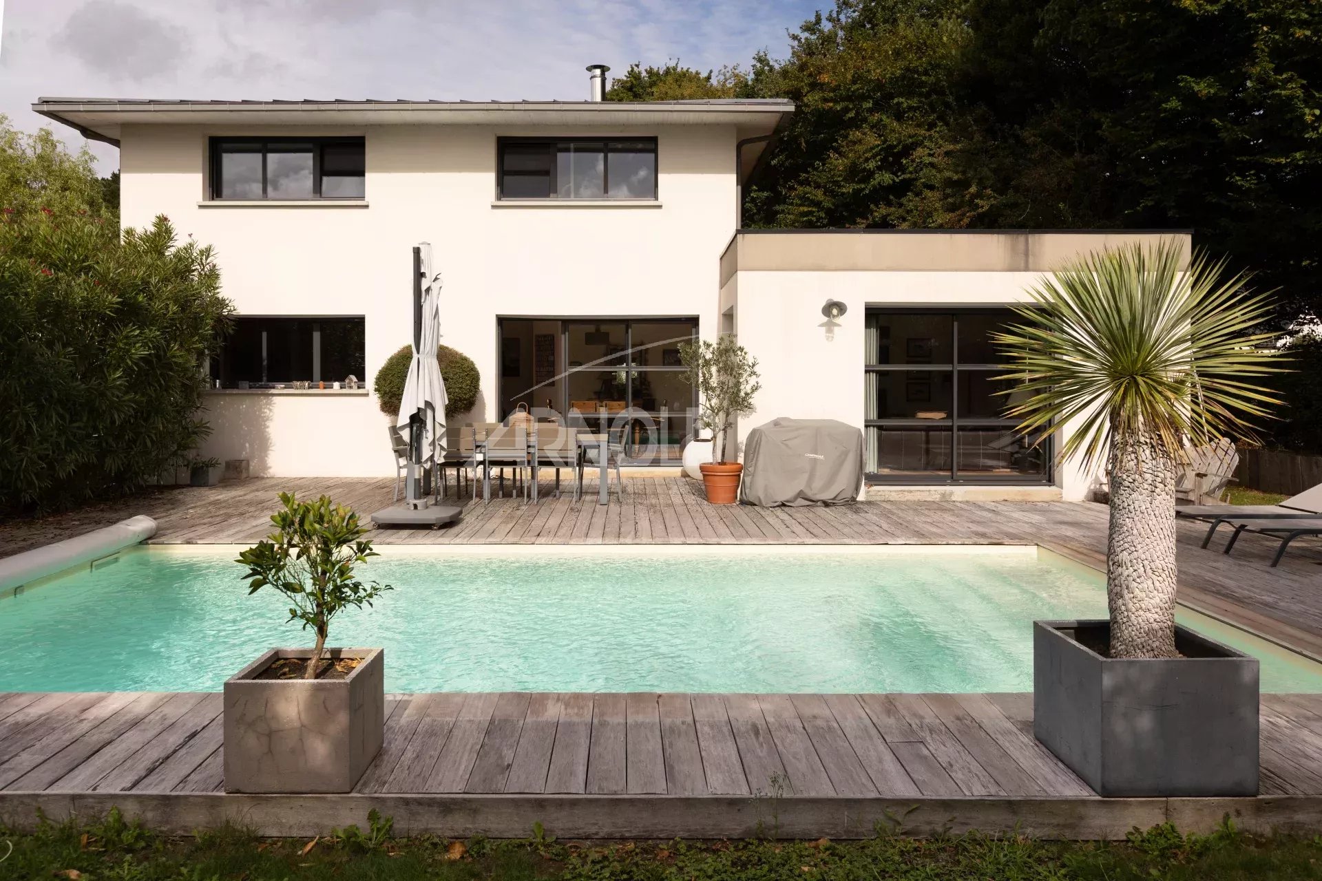Contemporary house with swimming pool and terrace in Vannes, surrounded by greenery.