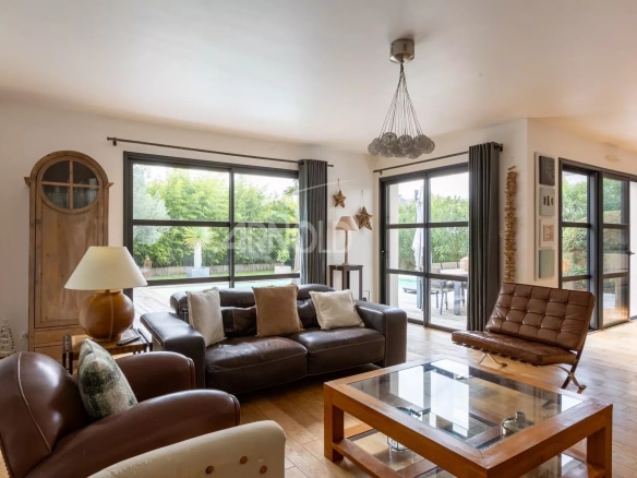 Interior of a contemporary house with a bright living room, leather sofa and a view of the outdoor pool.