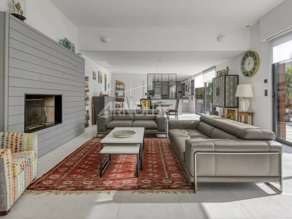 Interior of a contemporary villa in Pornichet, spacious living room with grey sofa and fireplace.