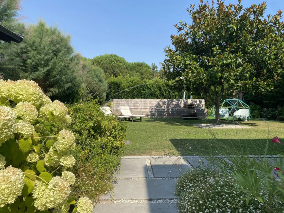 Garden of a contemporary villa in Pornichet with sun loungers and flowers.