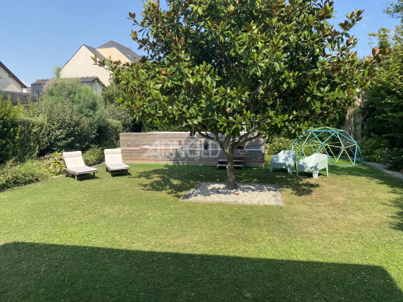 Garden of a contemporary villa in Pornichet with sun loungers and a tree.