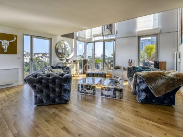 Interior of a luxury duplex with a bright living room and bay windows offering a view of Nantes.