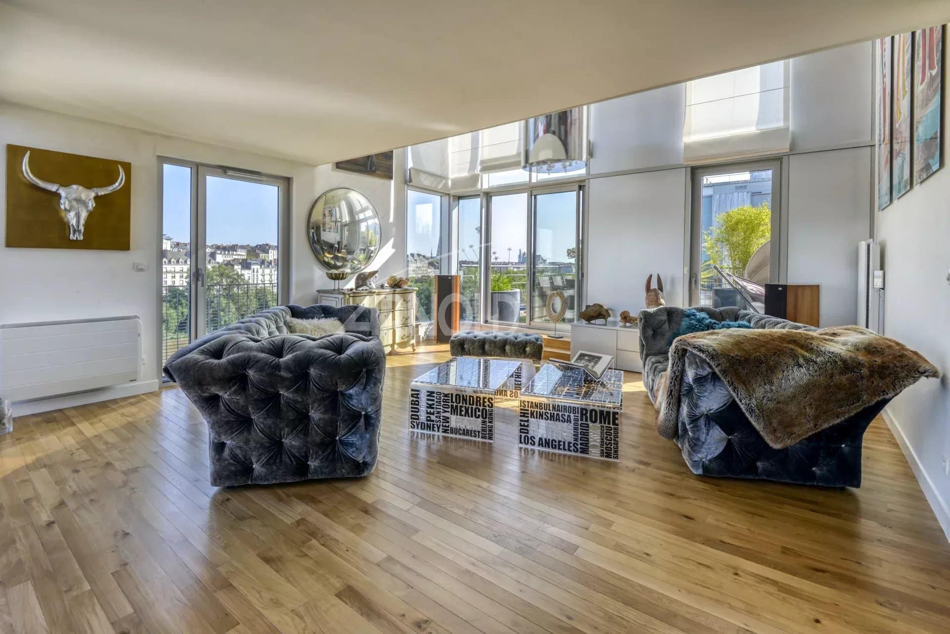 Interior of a luxury duplex with a bright living room and bay windows offering a view of Nantes.