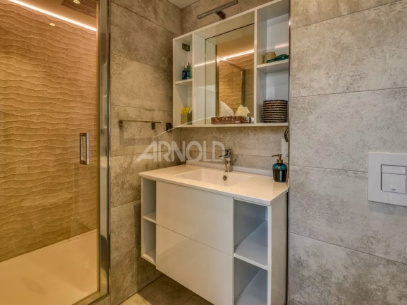 Salle de bain moderne avec douche et meuble lavabo dans un appartement rénové.