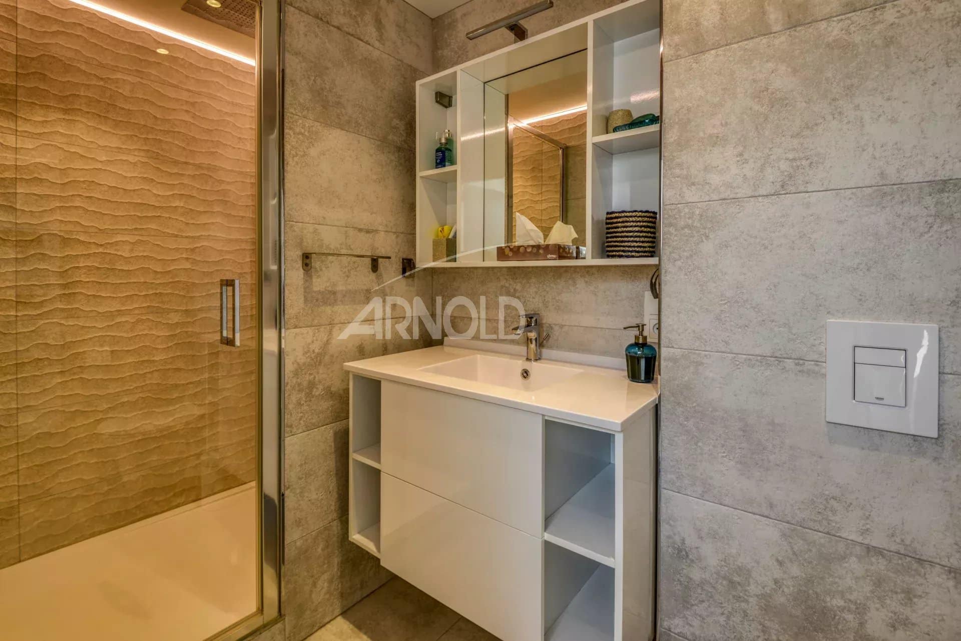 Salle de bain moderne avec douche et meuble lavabo dans un appartement rénové.