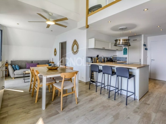 Intérieur d'un appartement en duplex avec vue sur la mer, cuisine ouverte et salon lumineux.
