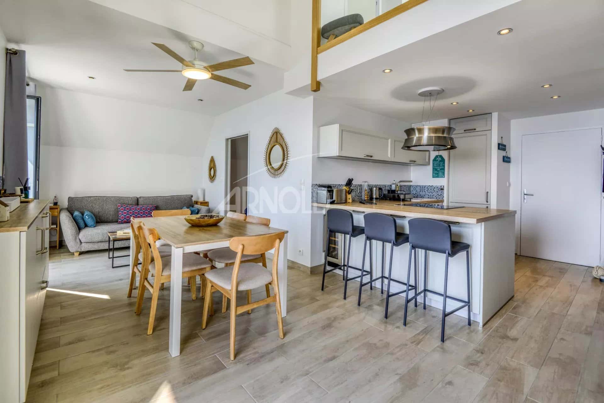 Intérieur d'un appartement en duplex avec vue sur la mer, cuisine ouverte et salon lumineux.