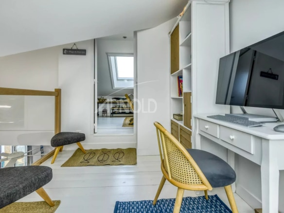 Intérieur d'un appartement rénové avec bureau et chaises, lumineux et moderne.