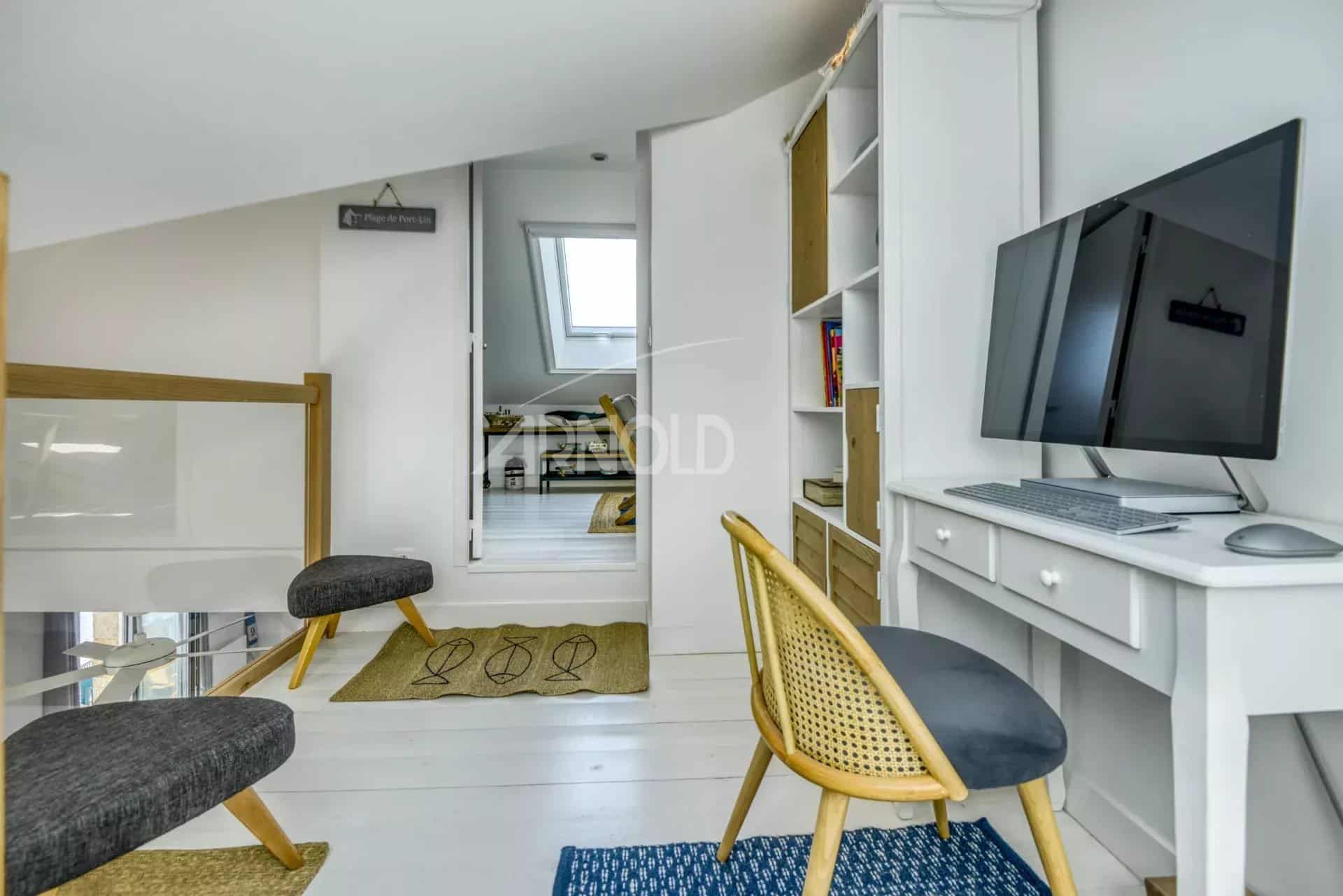 Intérieur d'un appartement rénové avec bureau et chaises, lumineux et moderne.