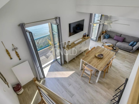 Intérieur d'un appartement en duplex avec vue sur la mer, salon lumineux et espace repas.