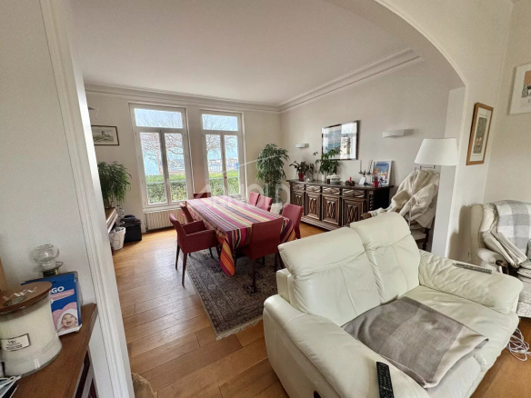 Interior of a bourgeois house with a large living room, a dining table and bright windows.
