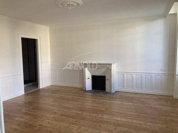 Interior of a renovated apartment with parquet flooring and fireplace, white walls, bright.