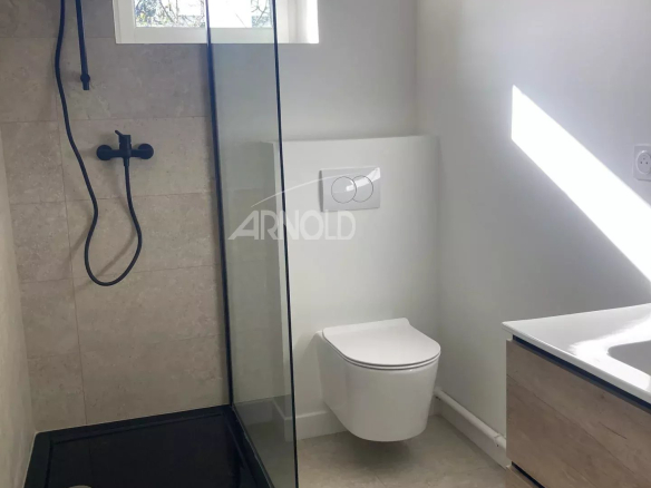 Modern bathroom with walk-in shower and toilet, recently renovated.