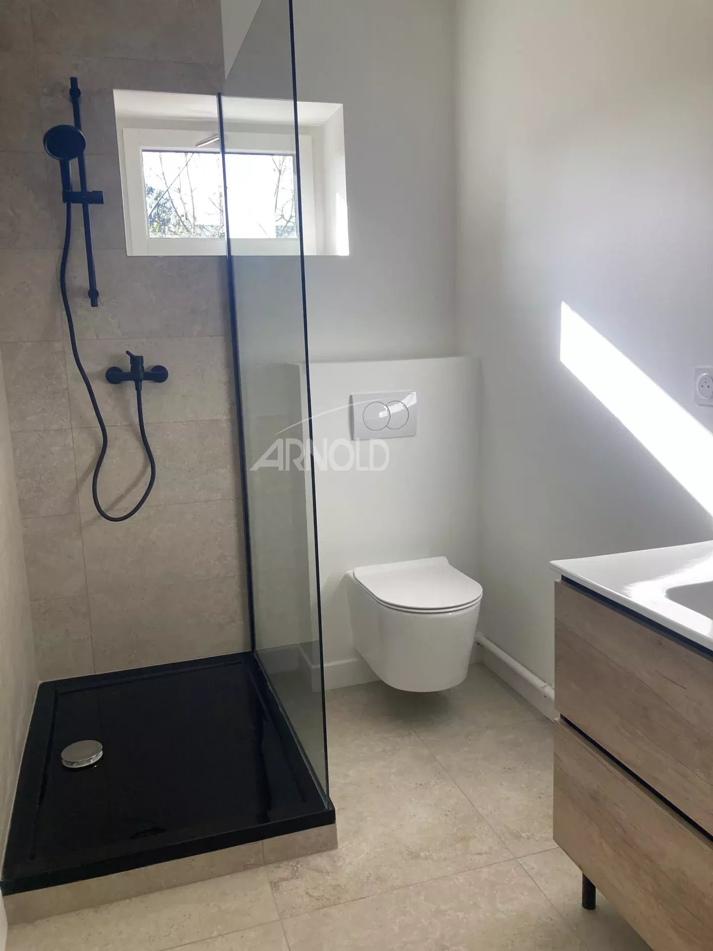Modern bathroom with walk-in shower and toilet, recently renovated.