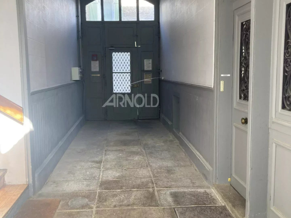 Entrance to an old building with a stone floor and grey-painted walls.