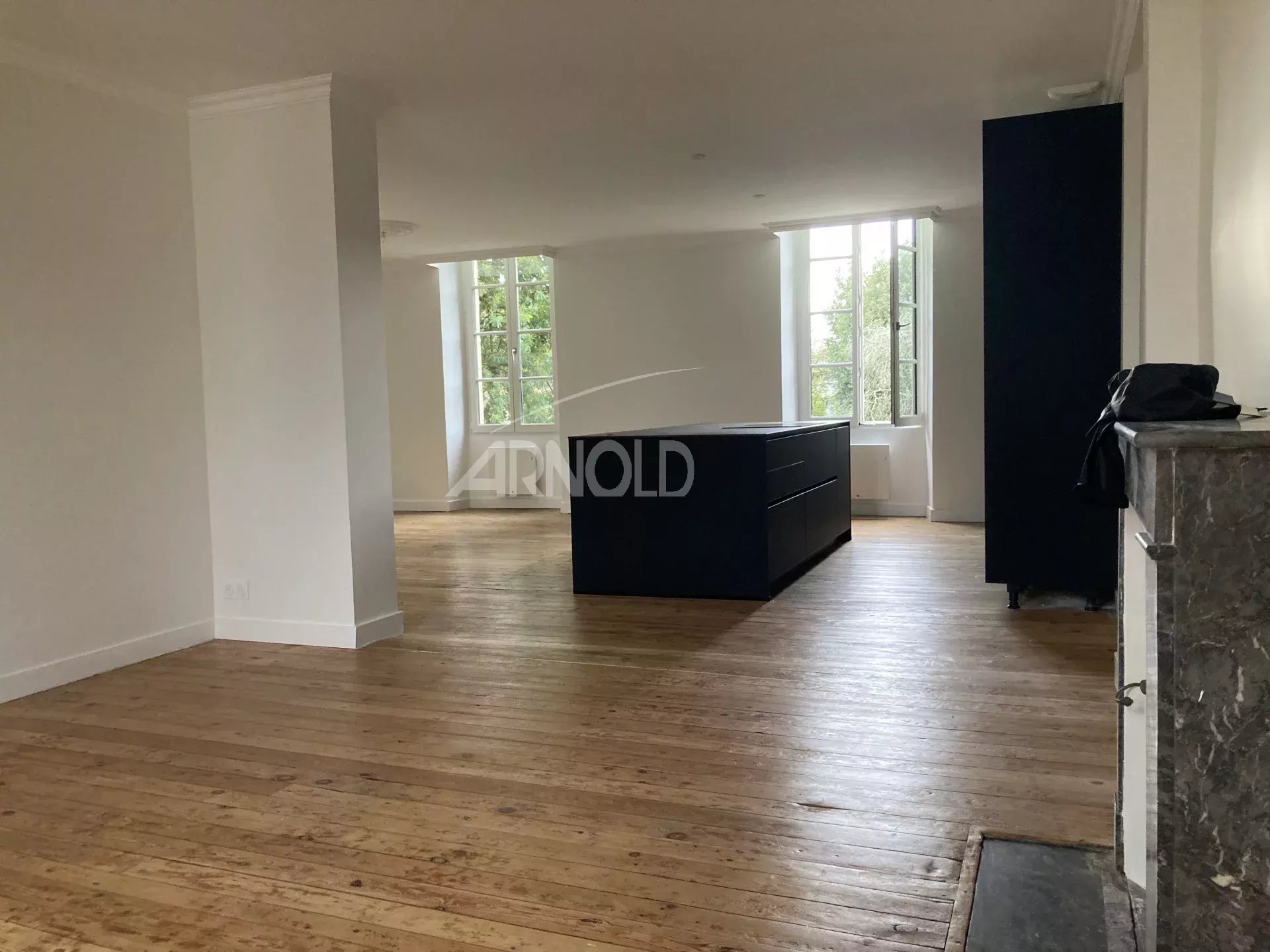 Interior of a renovated apartment with wooden flooring and an open kitchen, bright and spacious.