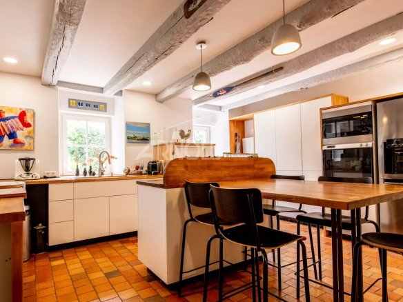Modern kitchen with central island and integrated appliances in a stone farmhouse.