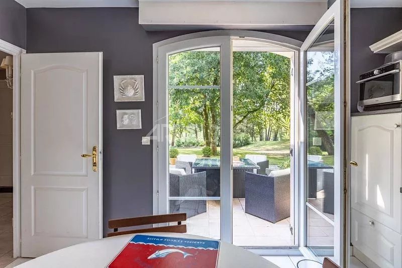 Intérieur d'une maison à Vannes avec portes-fenêtres donnant sur un jardin verdoyant.