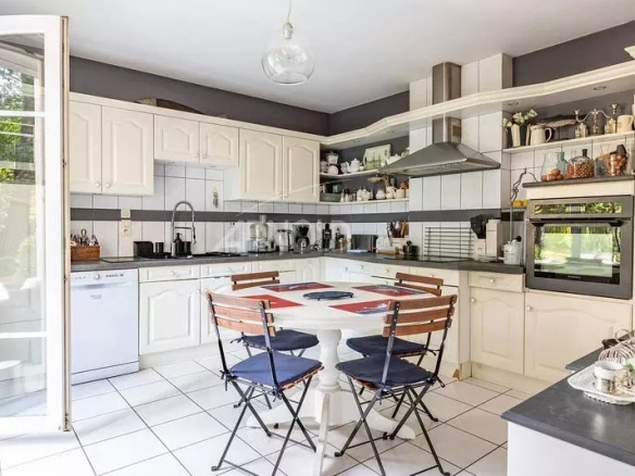 Cuisine moderne et lumineuse d'une maison à Vannes, avec table et chaises, équipements intégrés.