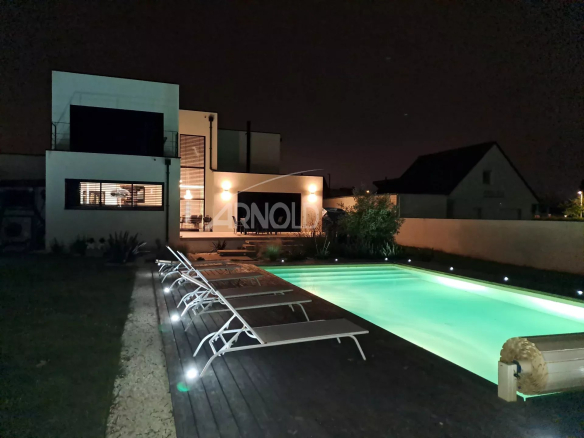 Contemporary villa with illuminated swimming pool at night in Vannes
