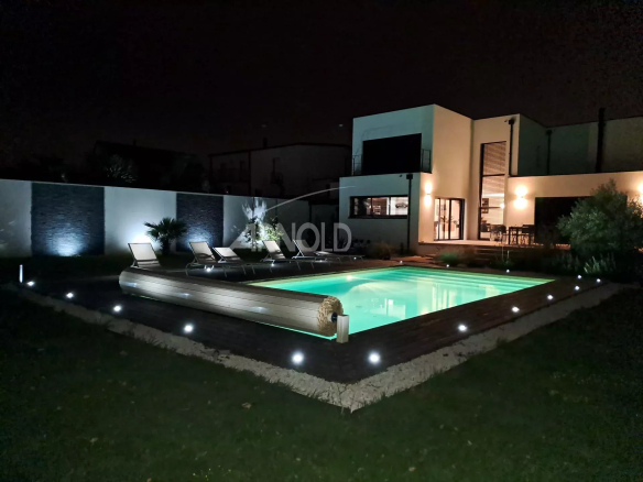 Contemporary villa with heated pool and terrace in Vannes, lit at night.