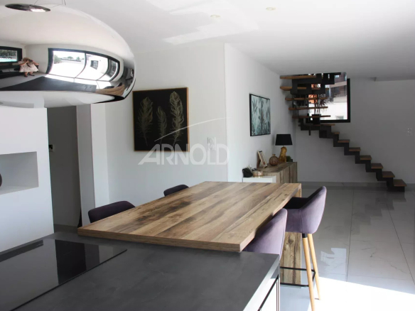 Interior of a contemporary villa in Vannes, with a large wooden table and a modern staircase.