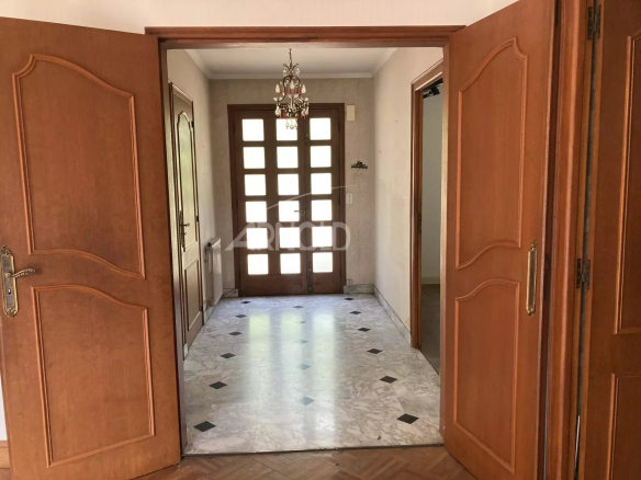 Entrée d'une maison spacieuse avec double porte en bois et carrelage au sol.